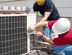 HVAC technicians repairing an outdoor AC unit on a rooftop in Greenville, NC