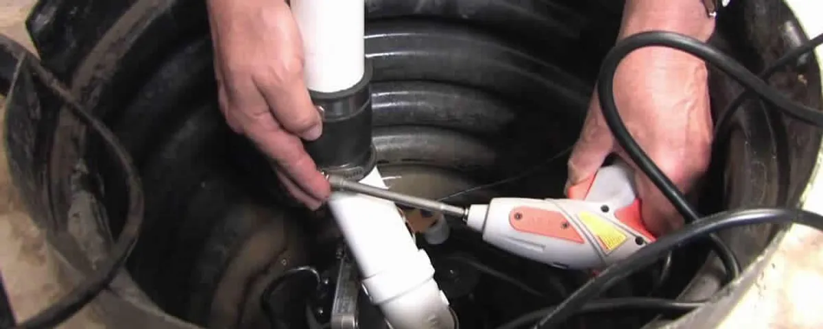 Sump pump installation technician connecting PVC discharge piping in Greenville, NC